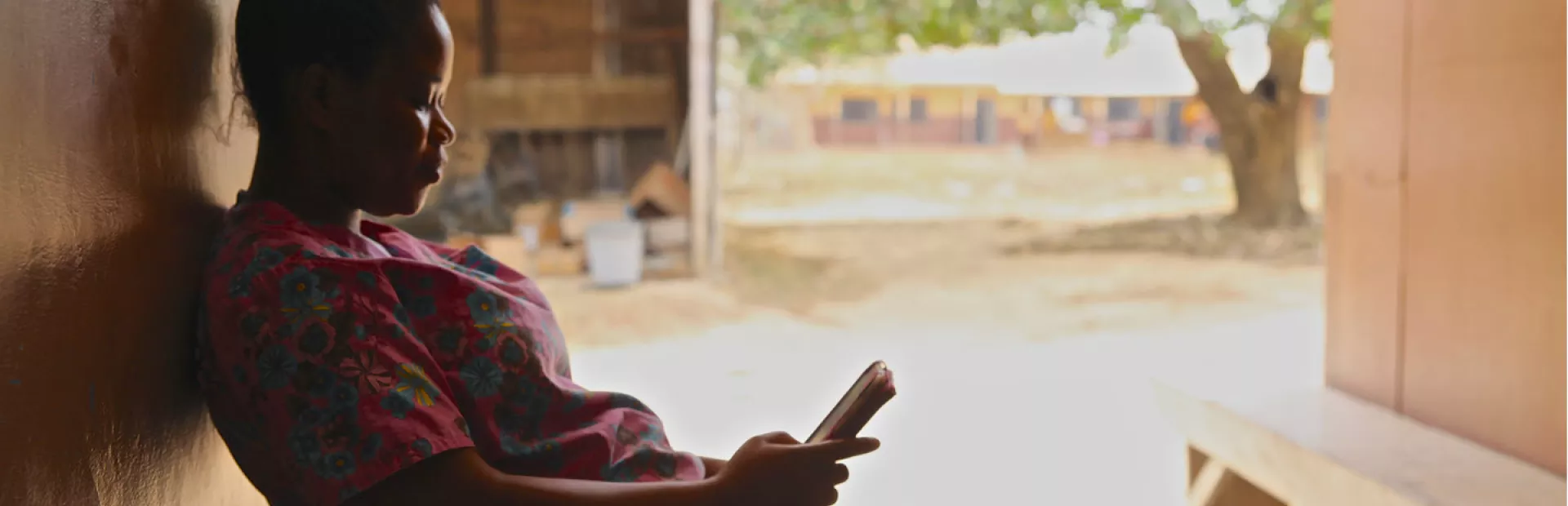 Telemedicine woman in Ghana on a bench looking at her mobile phone