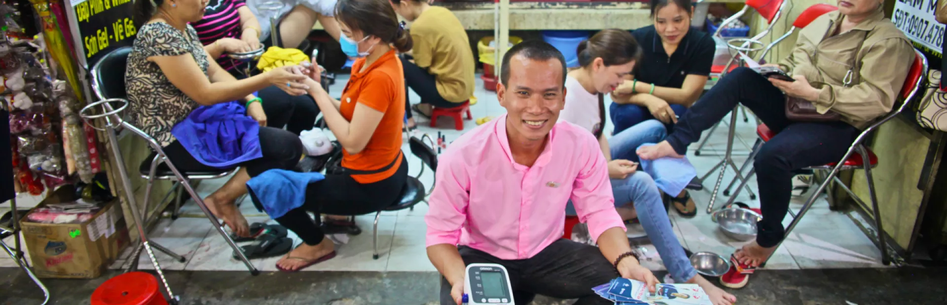 Person of the communities for healthy hearts Vietnam  holding flyers and blood pressure monitor in a cosmetic salon