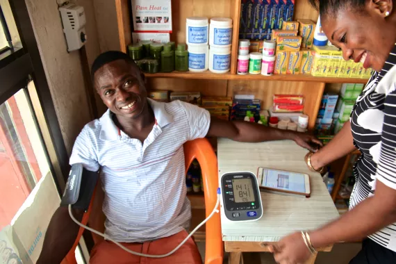 Image of patient in Ghana getting his blood pressure measured by a woman