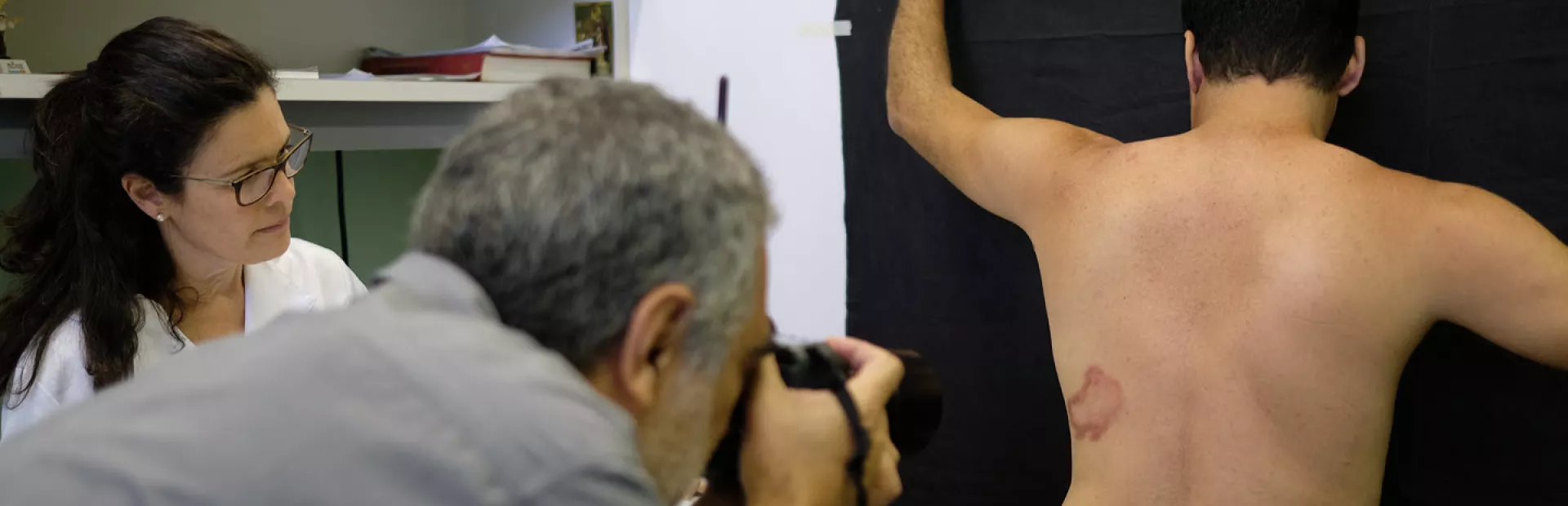 A photographer is taking a photo of the back of a patient for AI-enabled leprosy detection