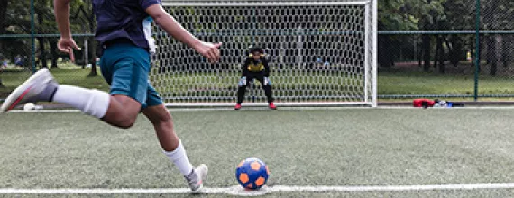 Two children playing soccer on a soccer court