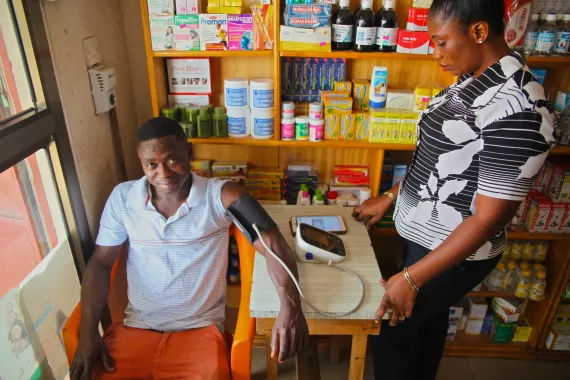 Image of patient in Ghana getting his blood pressure measured by a woman