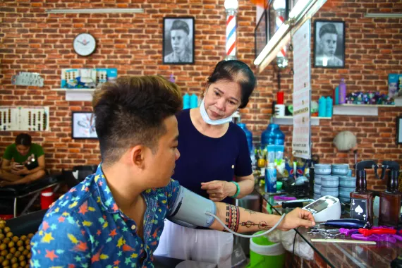Young man getting his blood pressure measured by a woman at a hair salon in Vietnam