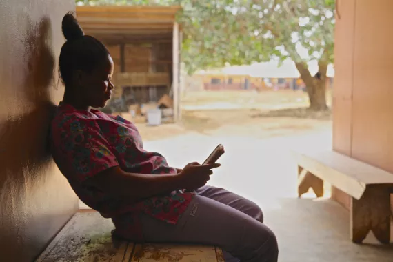 Telemedicine woman in Ghana on a bench looking at her mobile phone