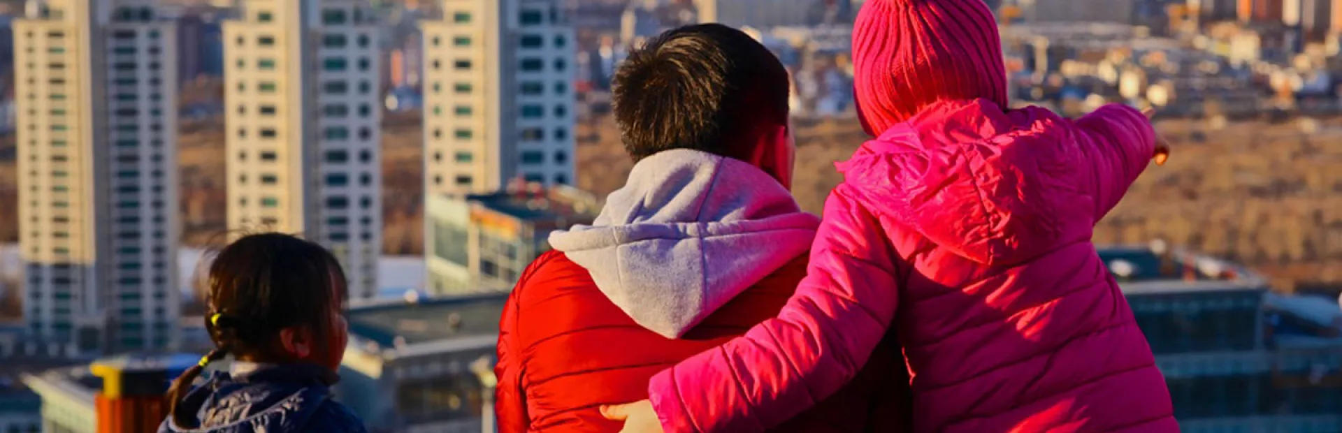 Man with 2 children looking over the city of Ulaanbataar, one child pointing to something