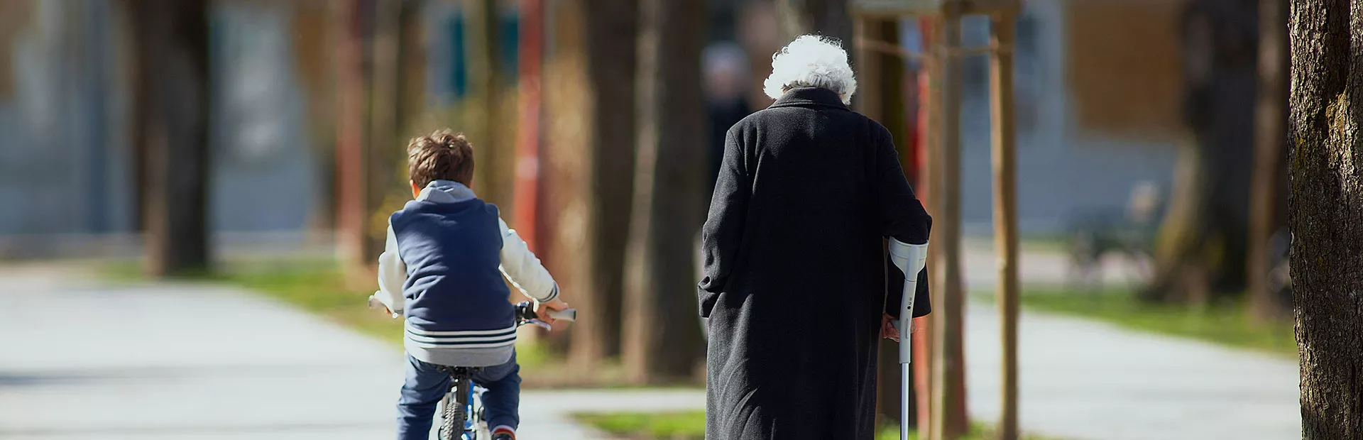 Young boy rides bike next to an elderly woman