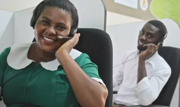 Image showing two telemedicine employees in Ghana with headsets at their workplace