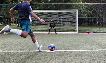 Two children playing soccer on a soccer court