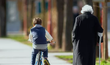 Young boy rides bike next to an elderly woman