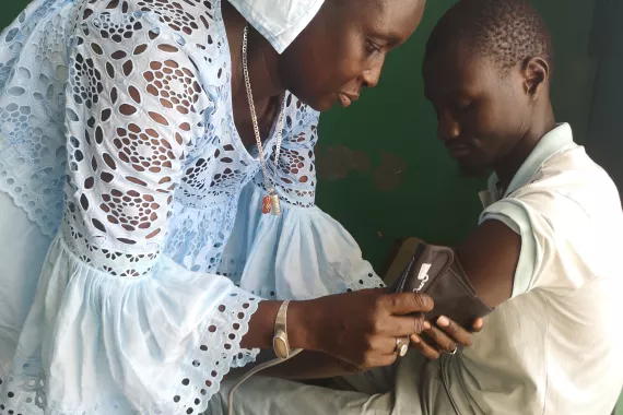 Female community health worker measuring blood pressure of a boy in Dakar