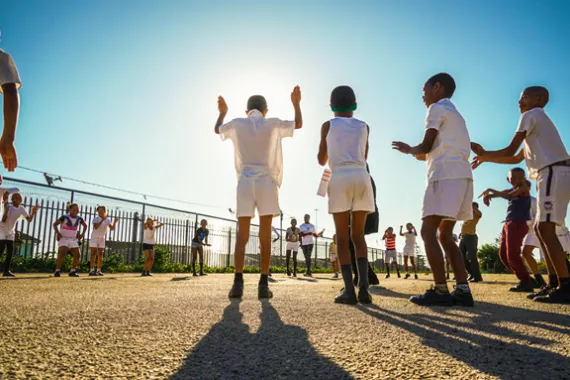 A group of children form a large circle while playing outside and learning about heart health