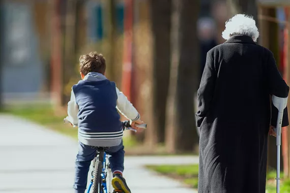 Young boy rides bike next to an elderly woman