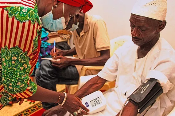 Image of an elderly patient in Senegal getting its blood pressure measured by a a nurse
