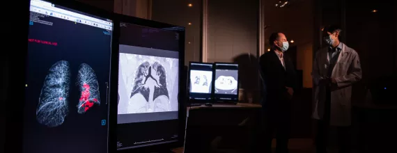 Image of scientists, wearing masks, discussing lung scans